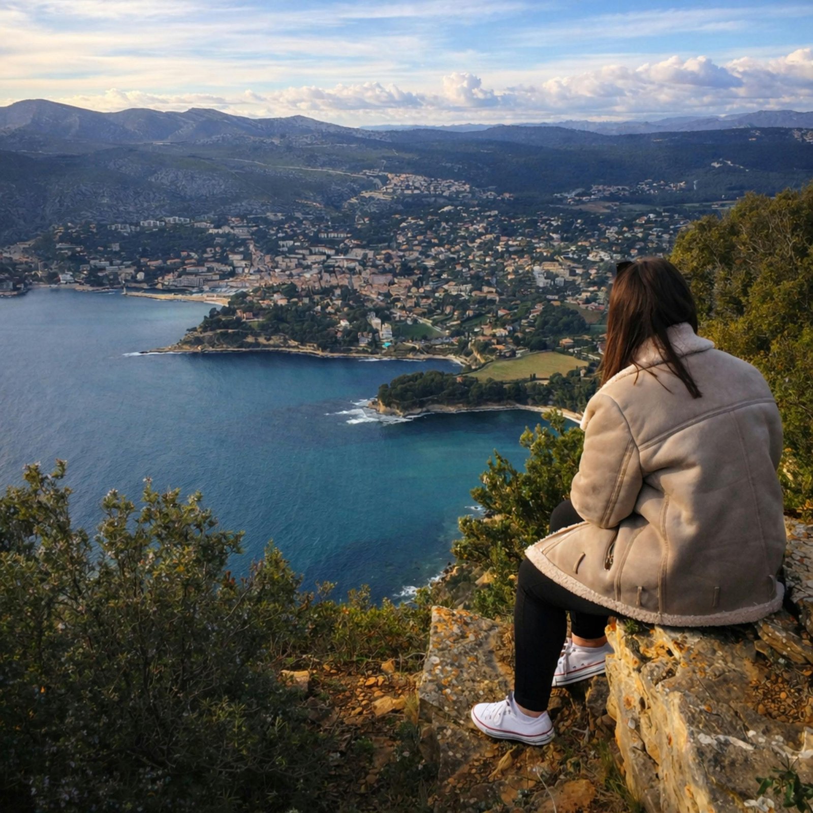 Woman sitting on cliff overlooking a coastal view in France