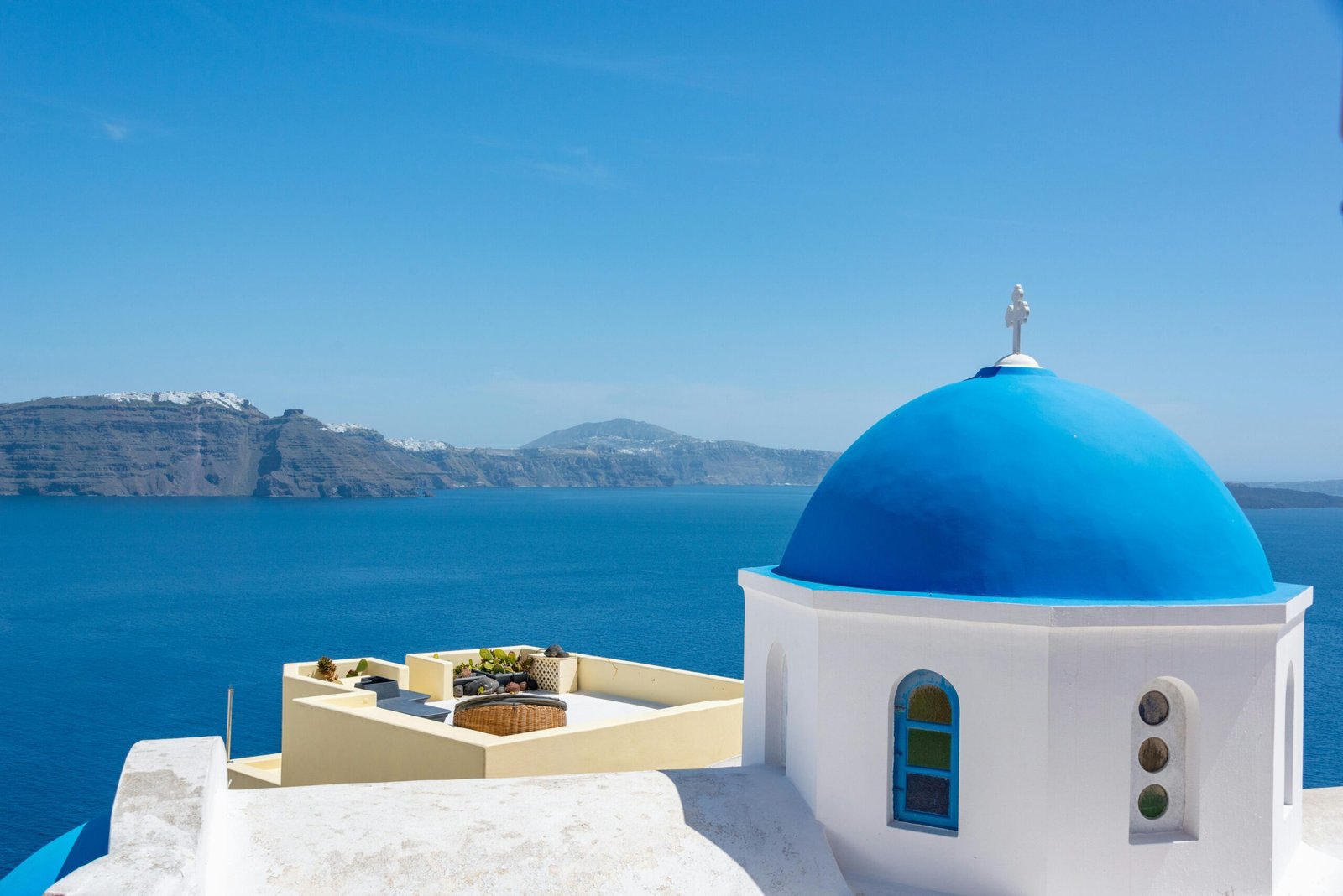 Iconic blue dome church in Santorini with a stunning view of the Aegean Sea.