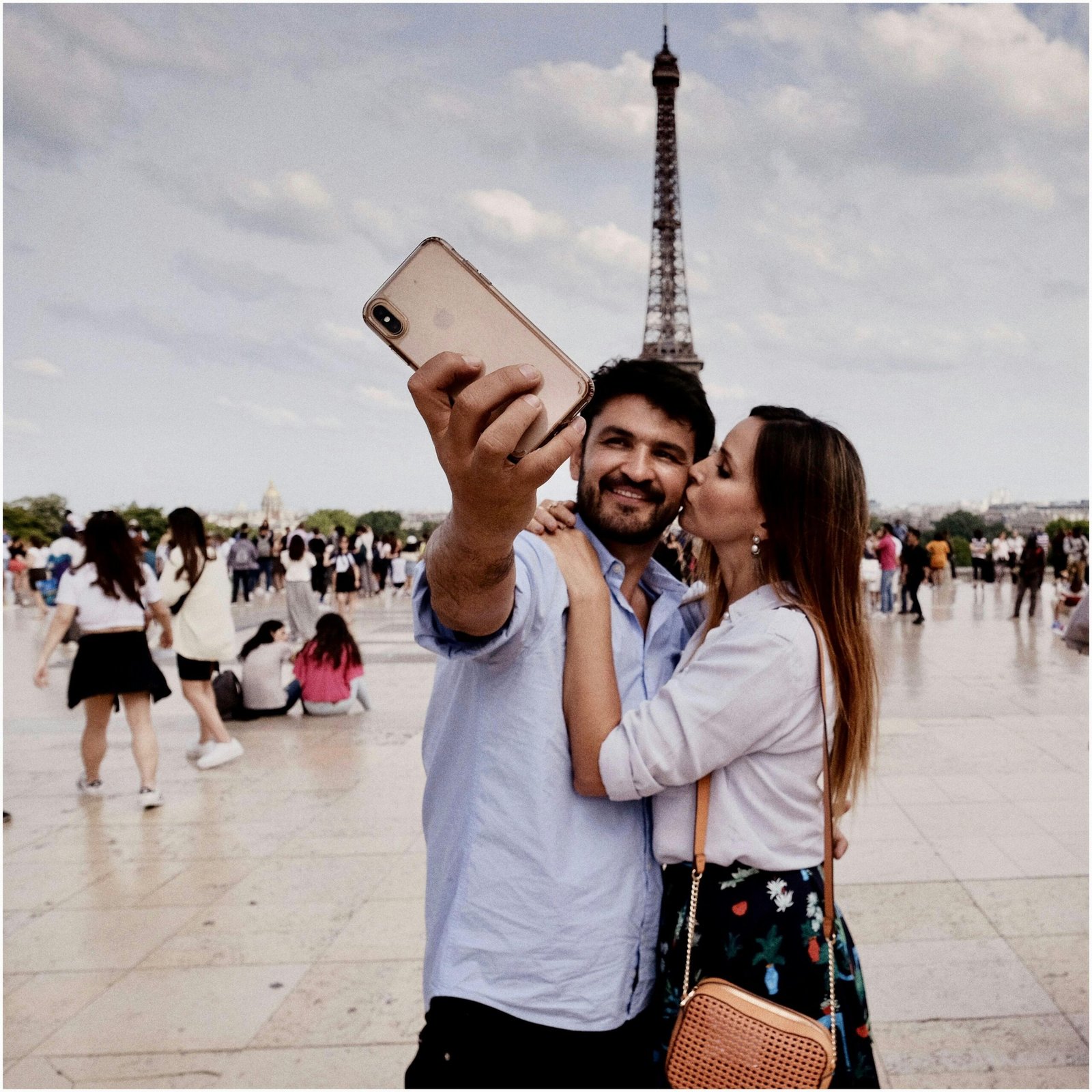 A couple embraces and takes a selfie in front of the Eiffel Tower, Paris.