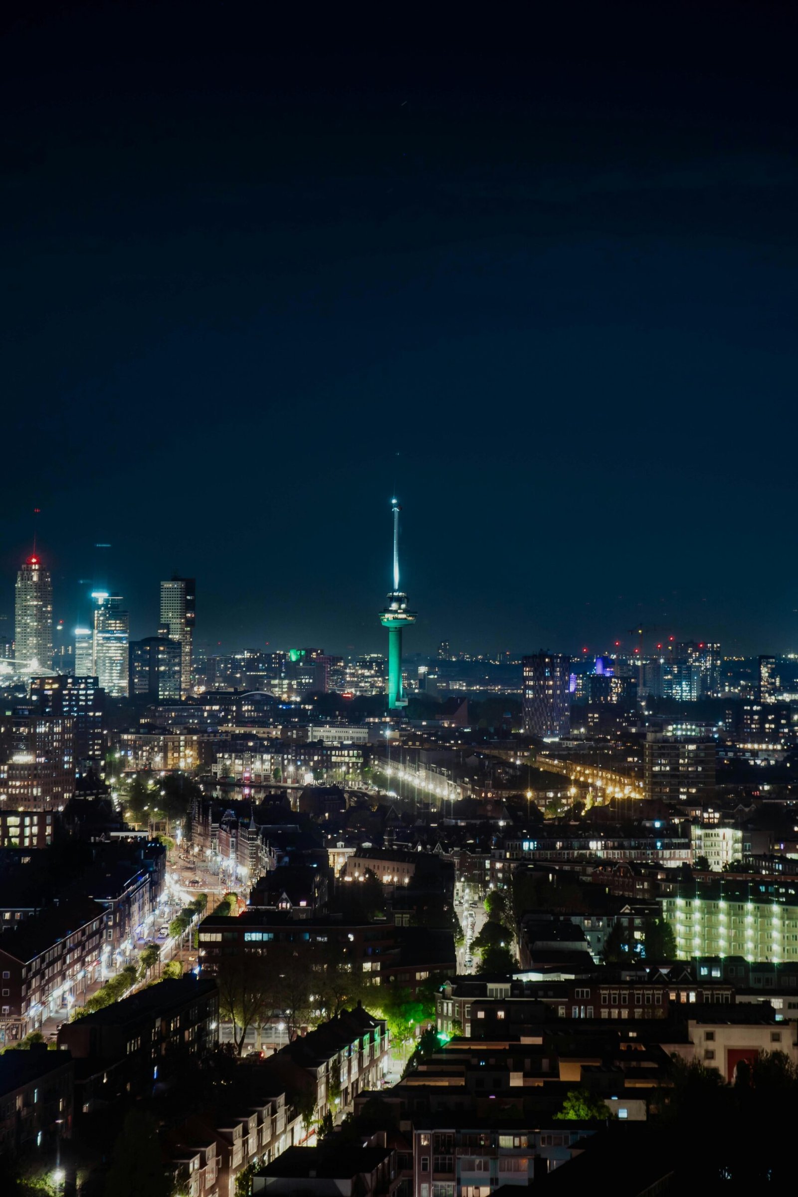 Aerial view of Rotterdam's illuminated skyline featuring the iconic Euromast at night.