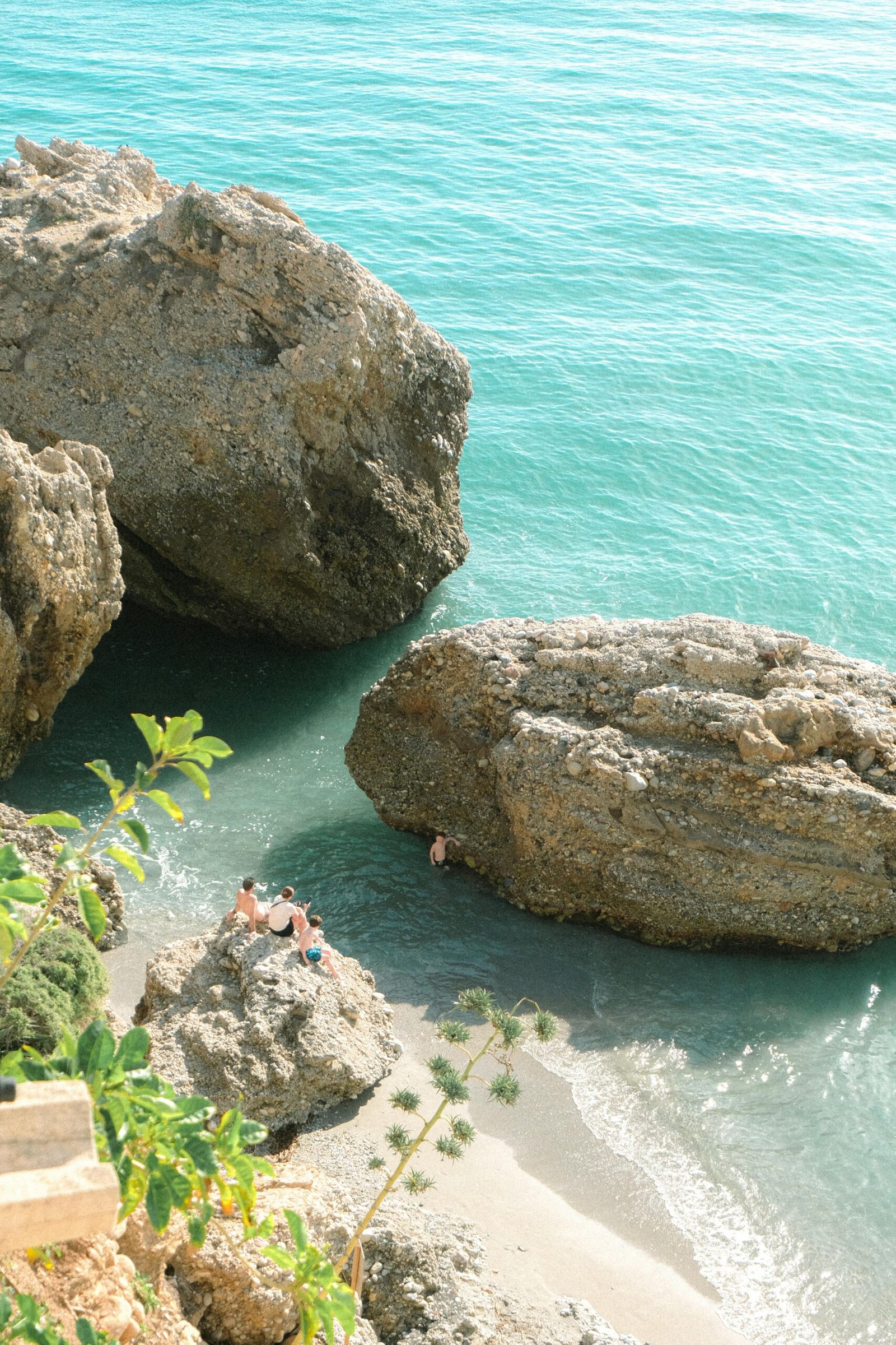 Discover a serene rocky cove in Nerja, Andalusia with clear turquoise waters and lush greenery