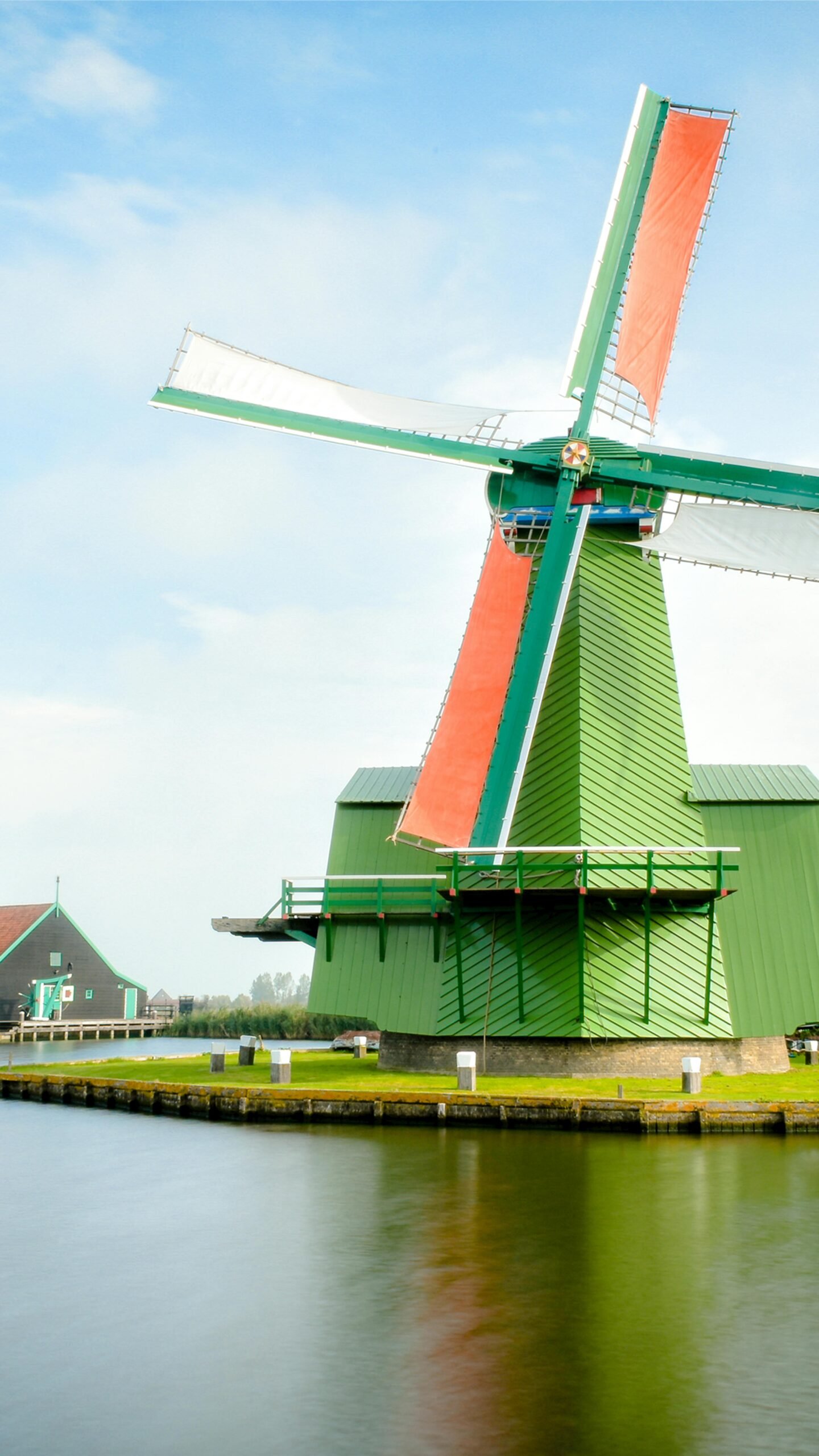 Charming view of a classic Dutch windmill in Zaanse Schans, Netherlands, showcasing vibrant architecture.